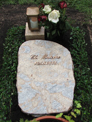 Liegendes Grabmal in München mit Blumen und einer Kerze auf einem kleinem Podest