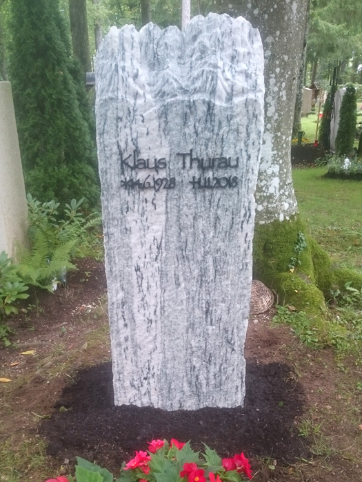 Stehendes Grabmal mit Blumen vor einem Baum in München