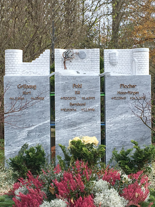 Drei stehende Grabmale nebeneinander mit Blumen in München
